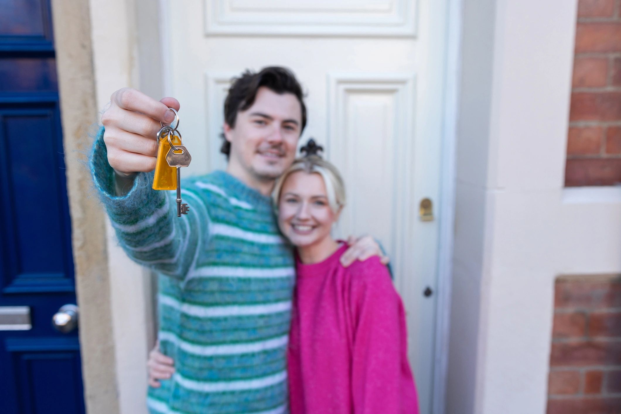 Couple holding keys outside their home